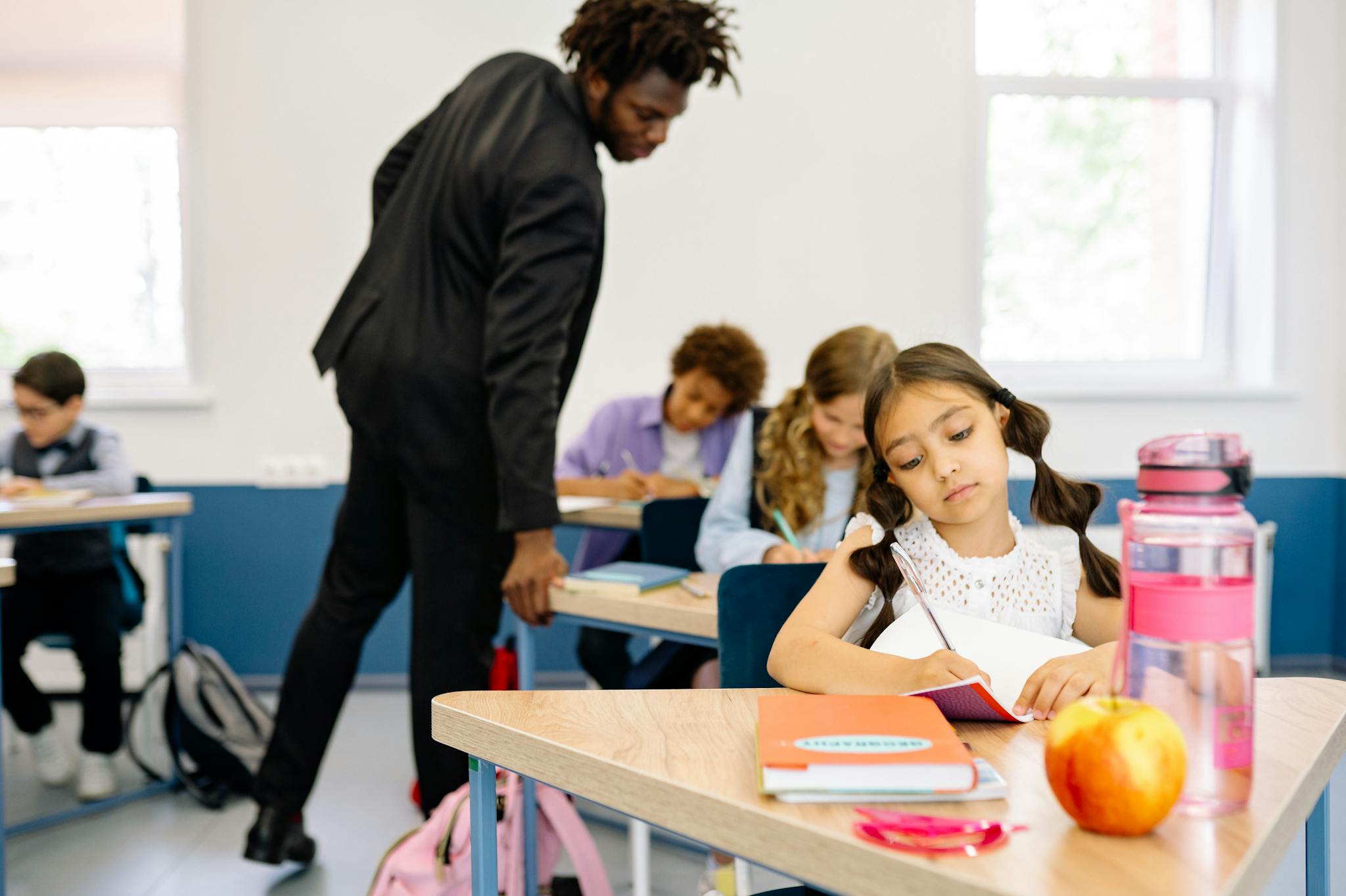 A classroom scene with children studying while a teacher provides guidance, fostering learning.